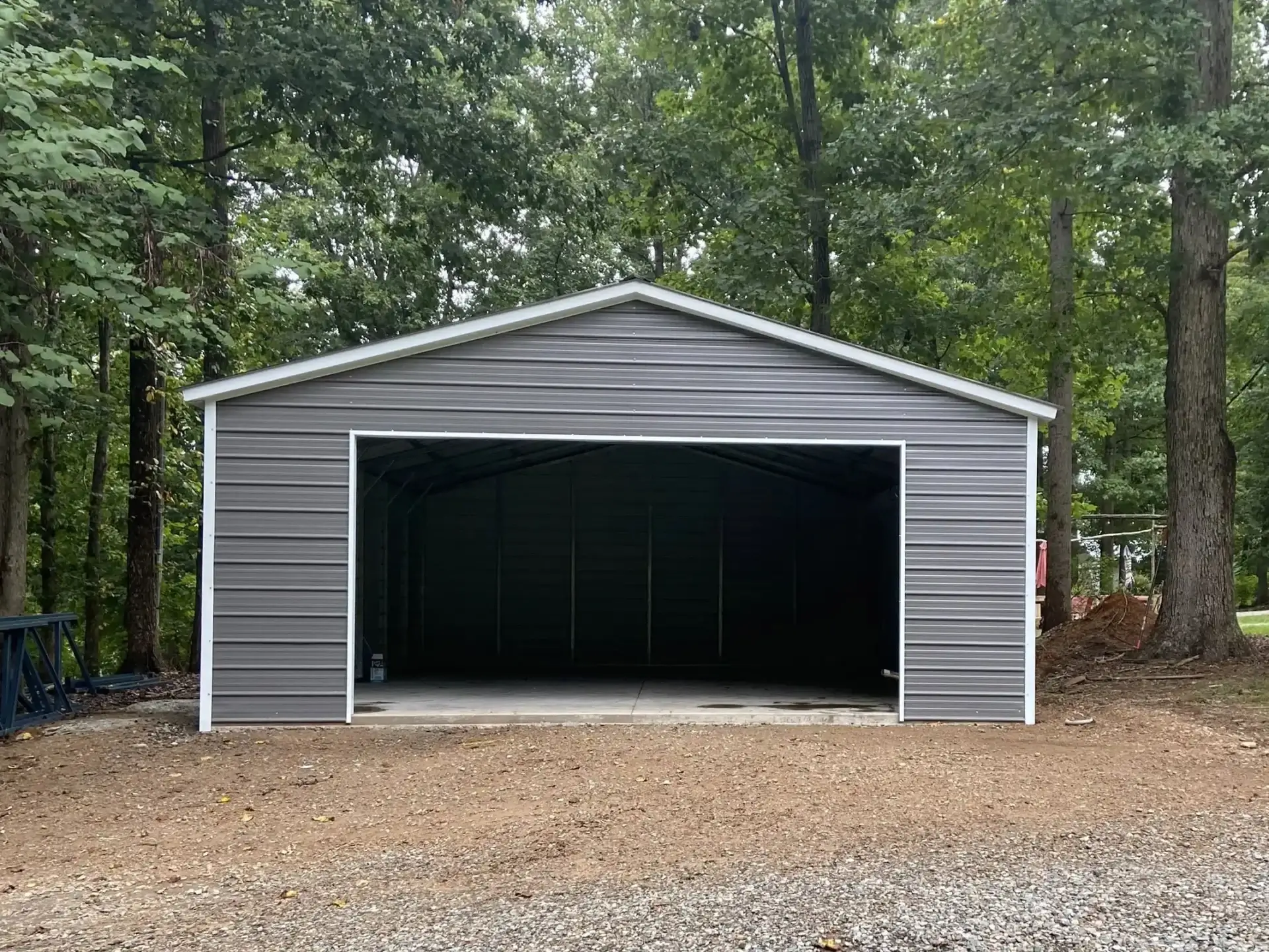 A gray garage with a door open in the middle of a field.