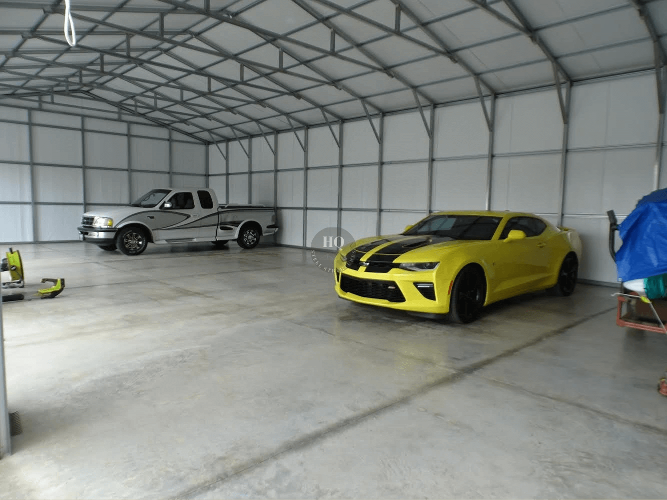 A yellow car and silver truck in a garage.
