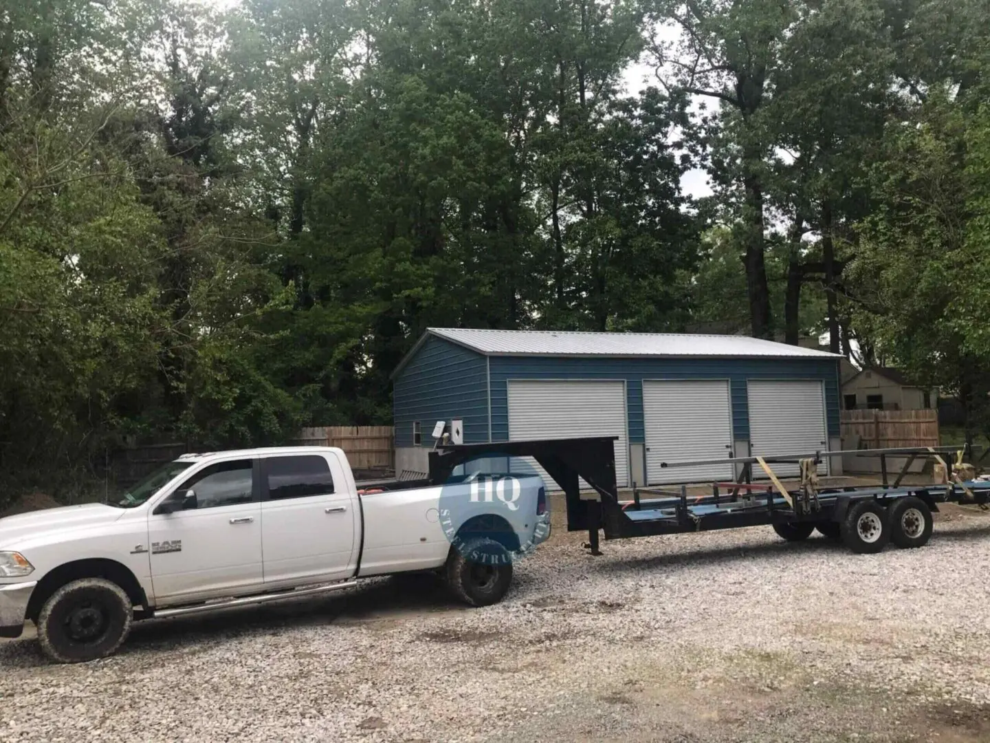 A white truck pulling a trailer with a blue shed.