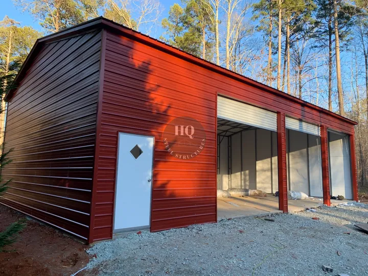 A red garage with a door open and trees in the background.